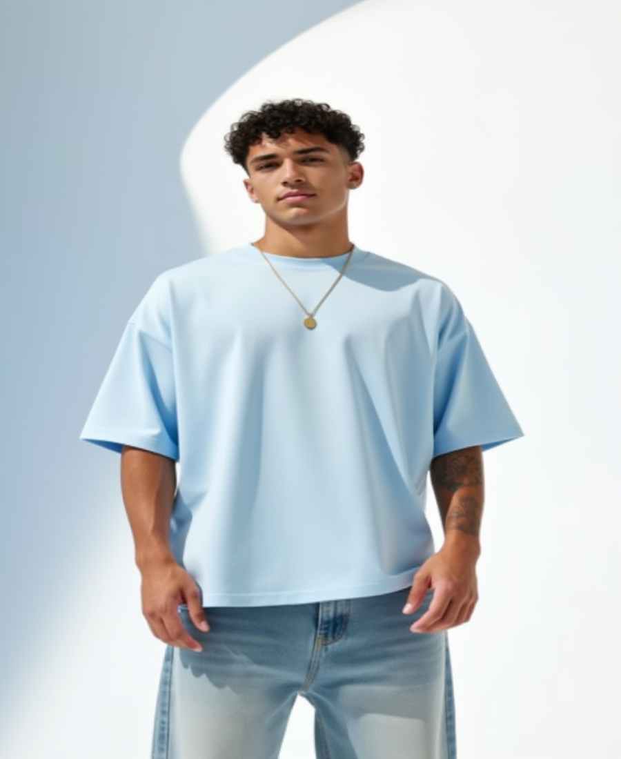 Man wearing a light blue oversized t-shirt and jeans against a light gray background