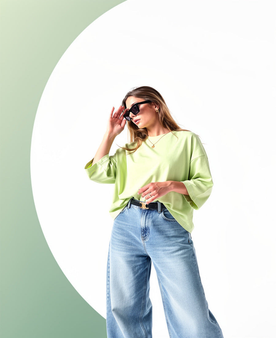Woman wearing a light green shirt and blue jeans against a green and white background