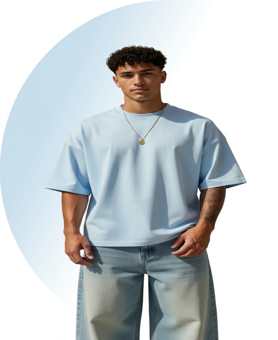 Man wearing a light blue t-shirt and jeans against a light blue background