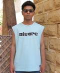Man wearing a light blue sleeveless shirt with 'nivare' text, standing against a stone wall.