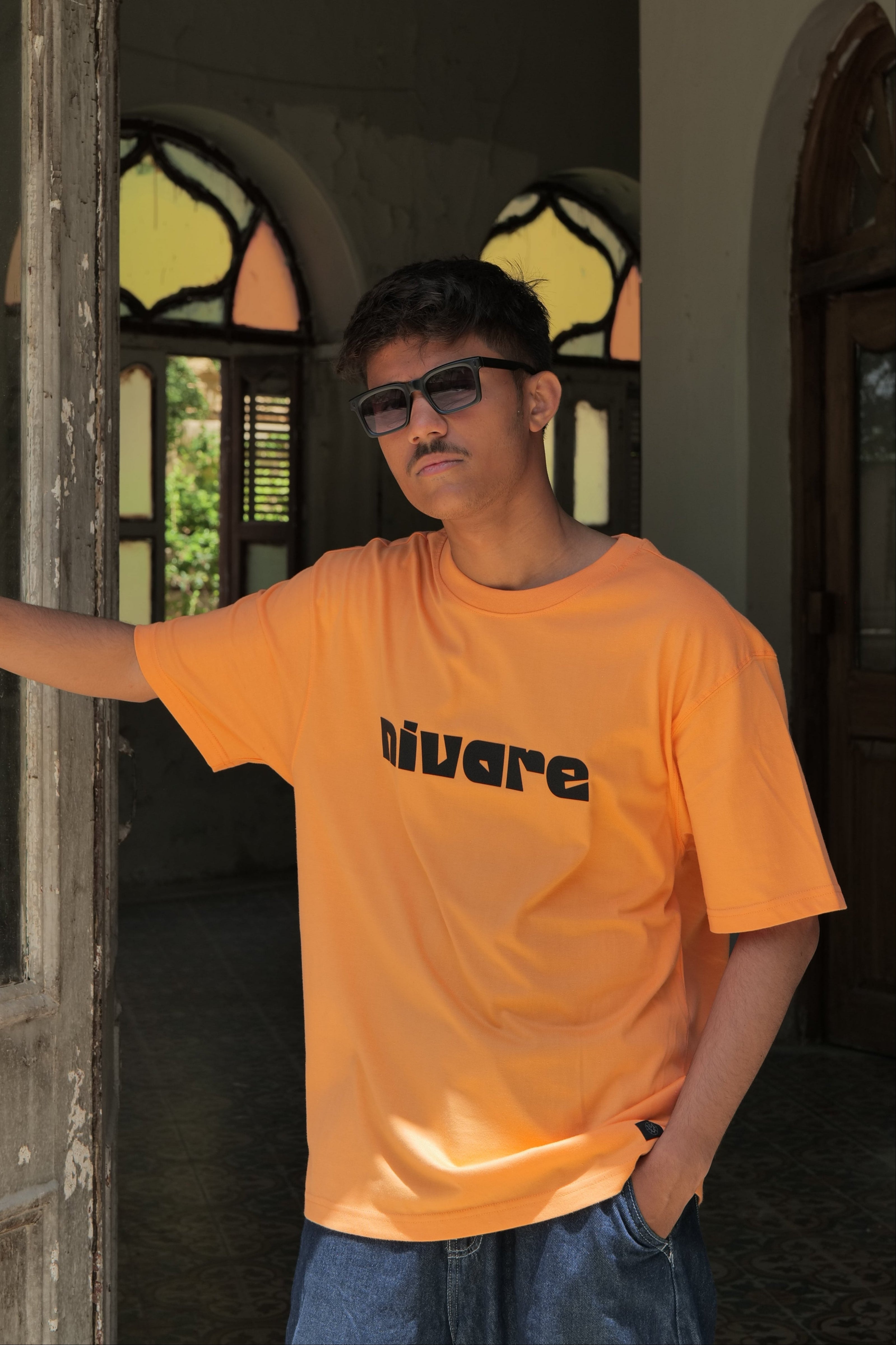 Person wearing an orange shirt with text, standing inside a vehicle.
