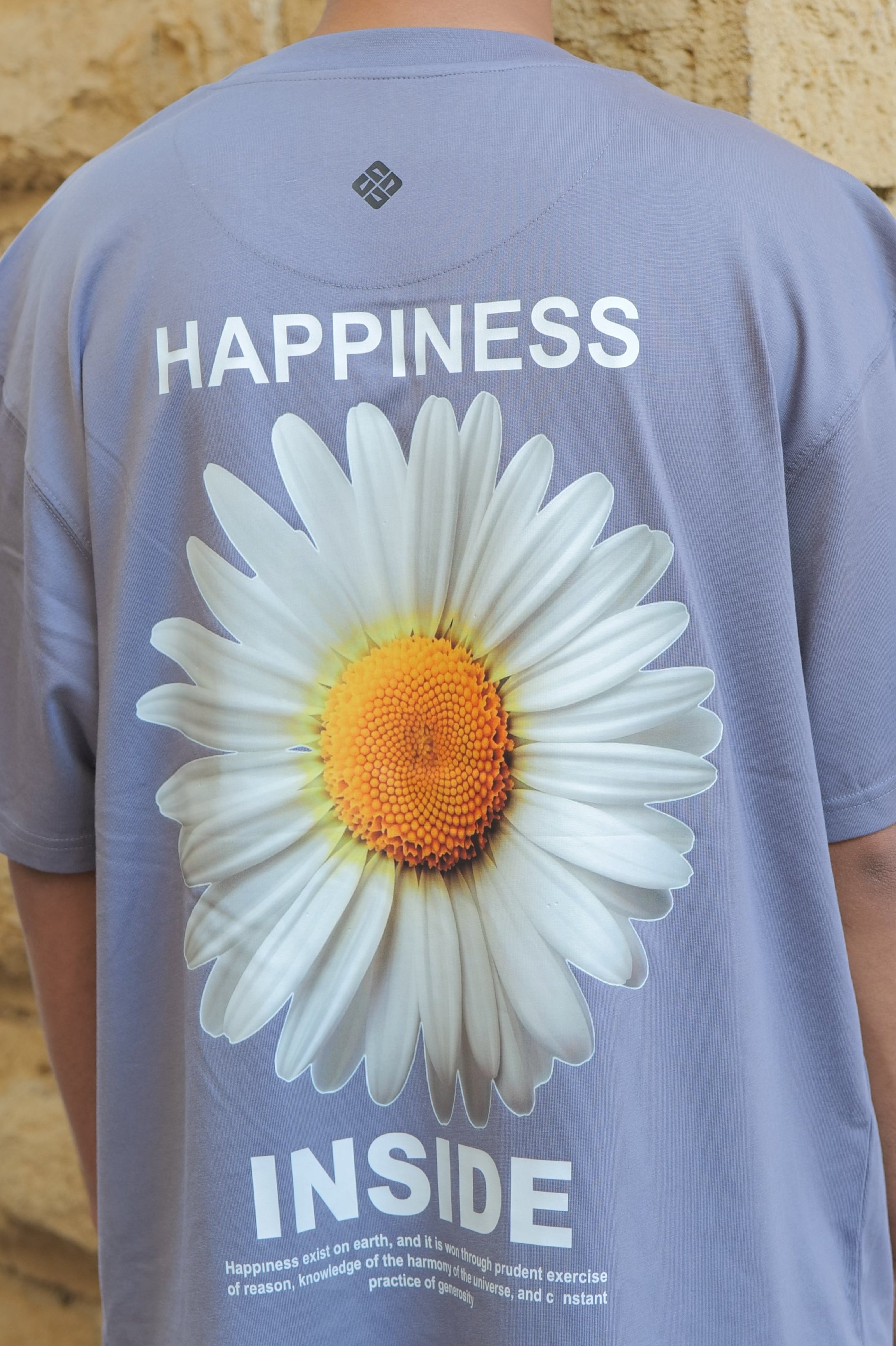 Person wearing a shirt with a daisy graphic and text outdoors.