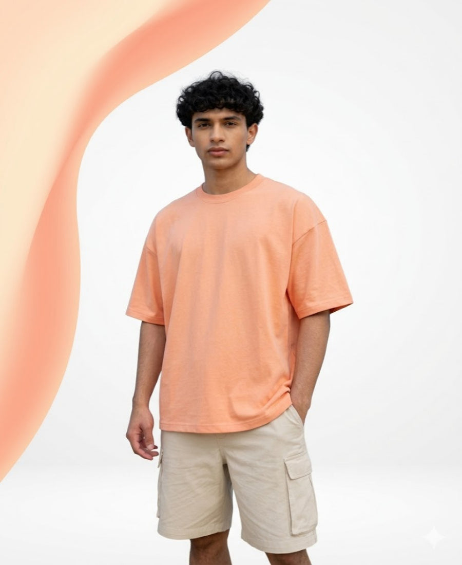 Person wearing an orange t-shirt and beige shorts against a white background with a large pink circle.