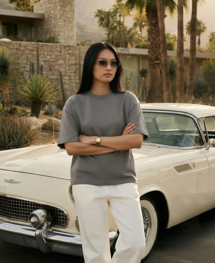 Woman standing in front of a vintage car with a desert landscape in the background