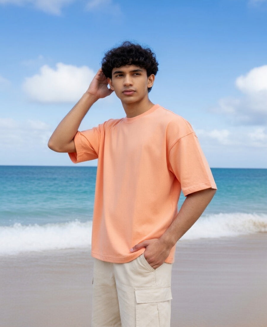 Person wearing an orange shirt on a beach with blue sky and ocean