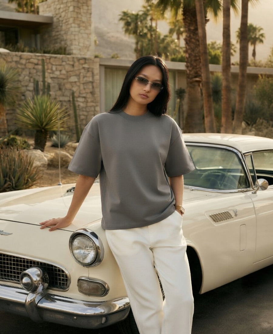 Woman standing next to a vintage car in a desert setting